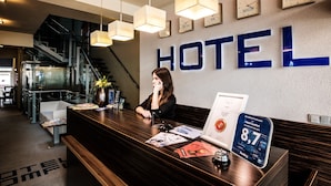 Un mostrador de recepción de hotel con un gran cartel que dice 'HOTEL', un reloj y un letrero de calificación 'Hotel Comfort'.