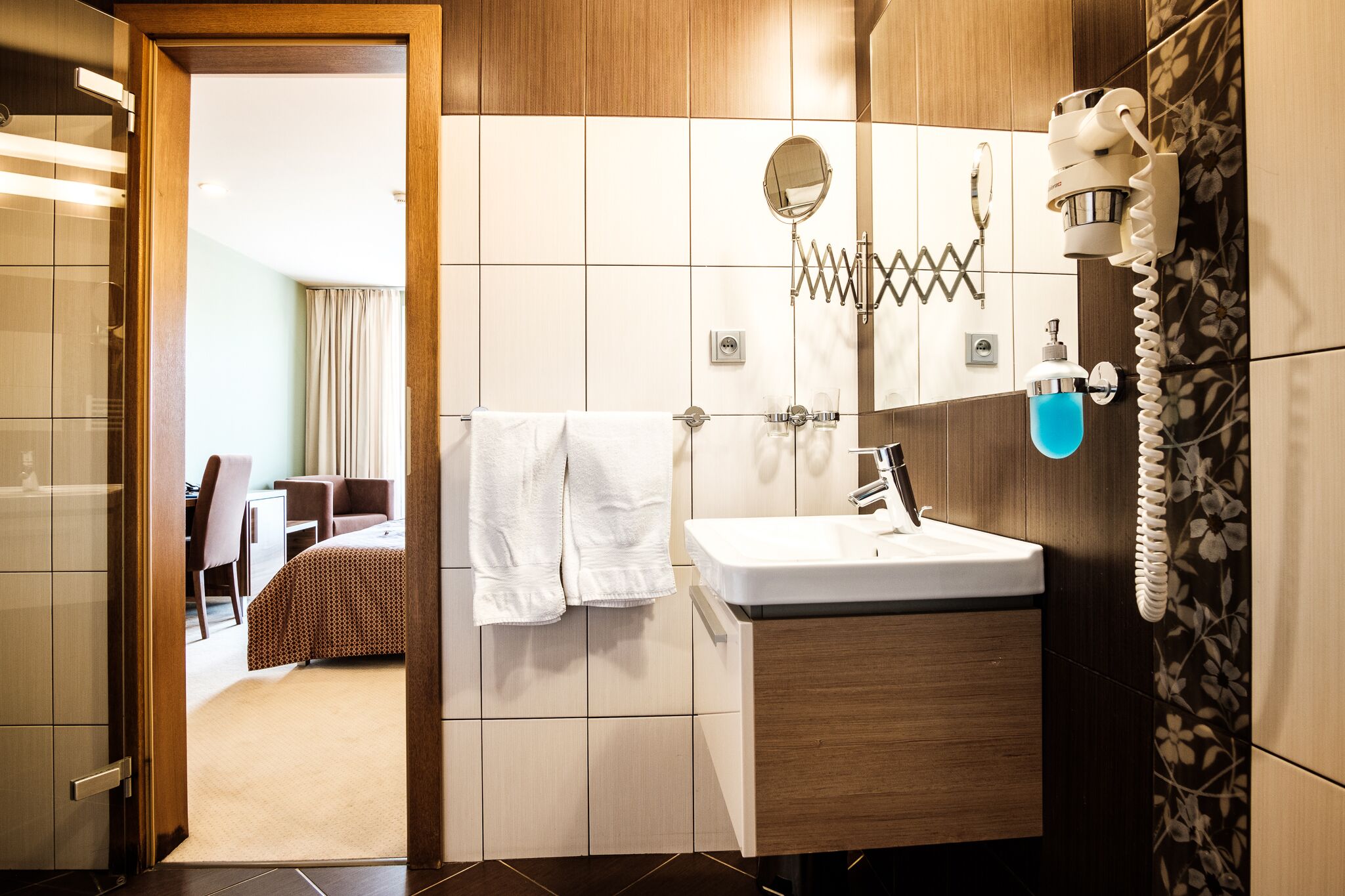 A modern bathroom with a sink, mirror, and towel rack.