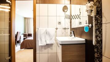 A modern bathroom with a sink, mirror, and towel rack.