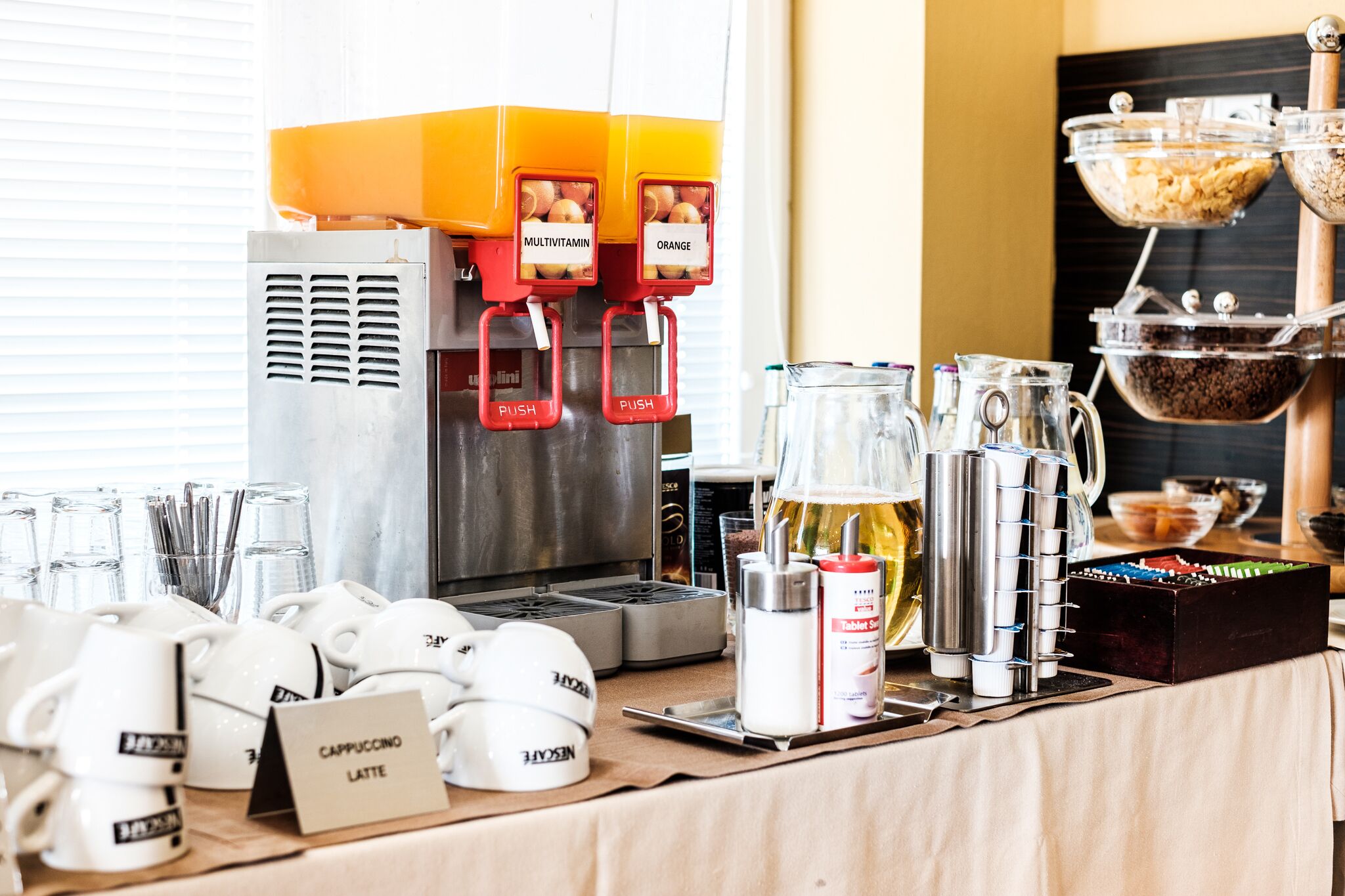A coffee station with a coffee machine, coffee cups, a milk pitcher, and a coffee grinder.