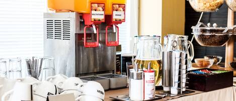 Una estación de café con una máquina de café, tazas, una jarra de leche y un molinillo de café.