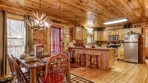 Una cabaña de madera con comedor, cocina y bar.