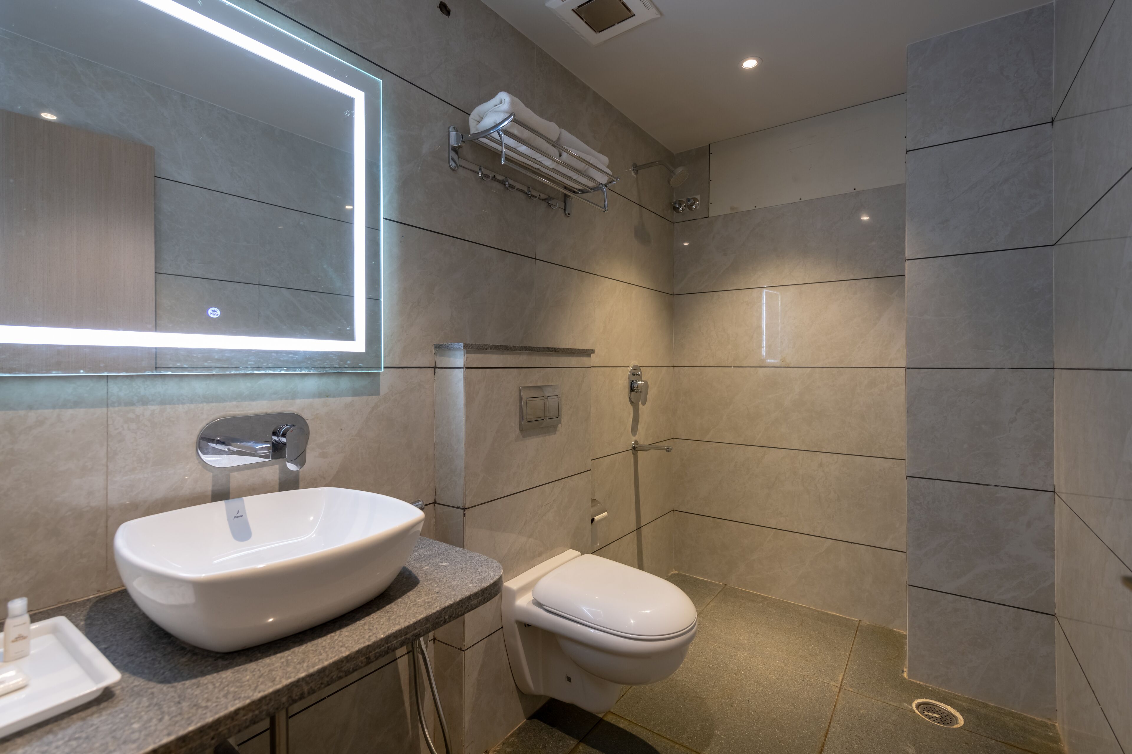 A modern bathroom with a large mirror, a sink, and a toilet.