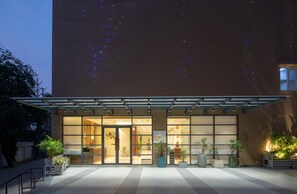 A hotel entrance with a covered patio, large windows, and potted plants. - Hotel Regal Grand (Bhopal)