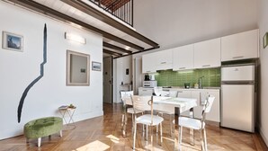 Een moderne keuken met witte kasten, een groene spatwand en een eethoek met een tafel en stoelen.