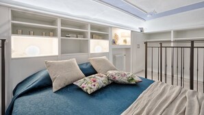 Une chambre à coucher avec un lit, des étagères intégrées, une fenêtre et une vue sur le ciel.