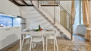 Une cuisine moderne avec des meubles blancs, un pare-feu bleu et un coin repas avec une table mise pour deux personnes.