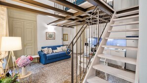 Un intérieur moderne avec un canapé bleu, une table ronde et un escalier doté d’une rampe en métal.