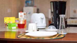 A kitchen counter with a coffee maker, a kettle, a glass pitcher, and various food items. - Cozy Room JKIA (Mlolongo)