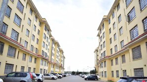 A row of yellow buildings with multiple windows and a parking lot in front. - Cozy Room JKIA (Mlolongo)