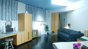 A hotel room with a bed, a sofa, a desk with a mirror, and a small table with a plant. - LA.FESTA - Adults Only (Takamatsu)
