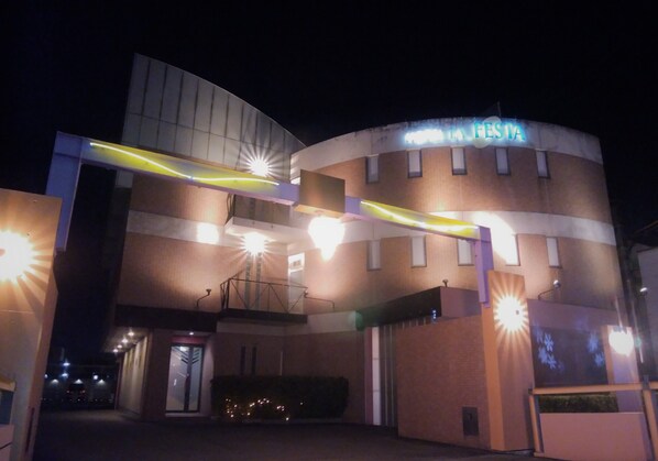 Un edificio con fachada curva, un cartel que dice "FESTA" y varias lámparas.