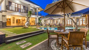 A two-story building with a swimming pool, outdoor seating area, and a well-maintained lawn. - Ayuna Suites Canggu By Zuzu (Tibubeneng)
