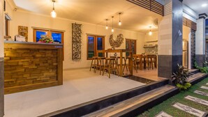 A modern kitchen with a wooden backsplash, a dining area with bar stools, and a staircase leading to an upper level. - Ayuna Suites Canggu By Zuzu (Tibubeneng)
