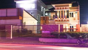 A modern two-story house with a balcony, a gated entrance, and a bicycle parked outside.