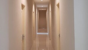 A long, narrow hallway with a shiny floor and recessed lighting.