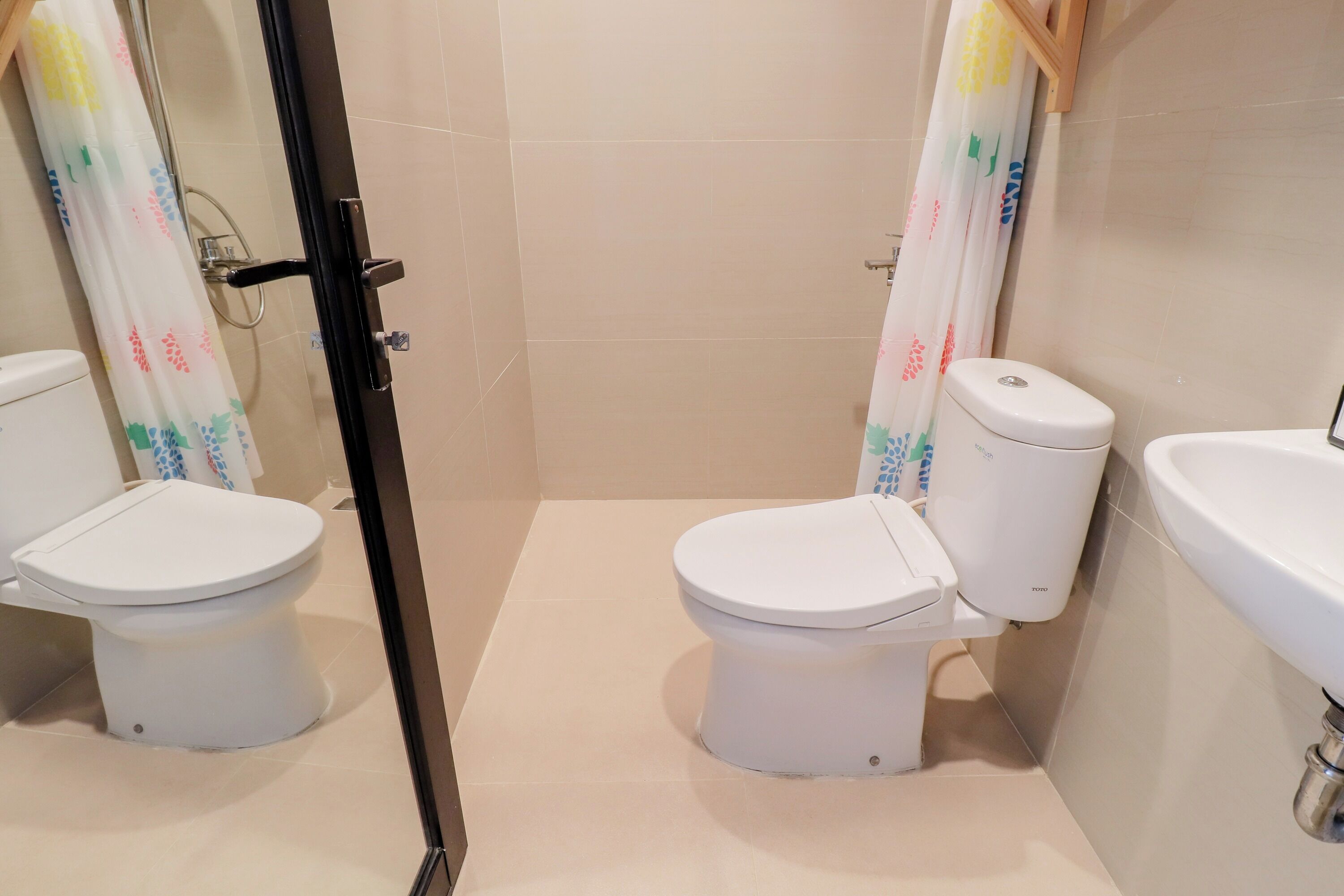A bathroom with two toilets, a shower, and a sink.