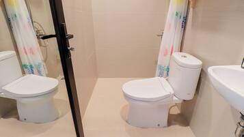 A bathroom with two toilets, a shower, and a sink.
