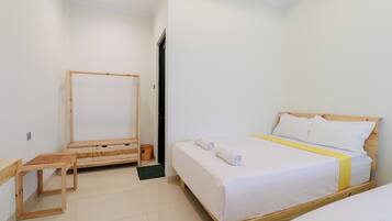 A bedroom with a bed, a wooden bench, a wardrobe, and a small trash bin.
