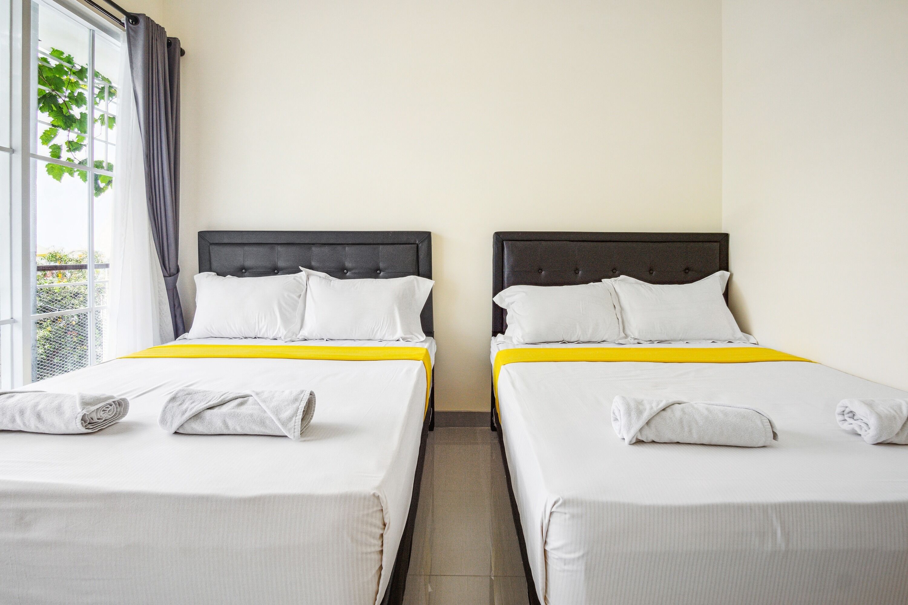 Two single beds with headboards, white bedding, and a yellow accent.