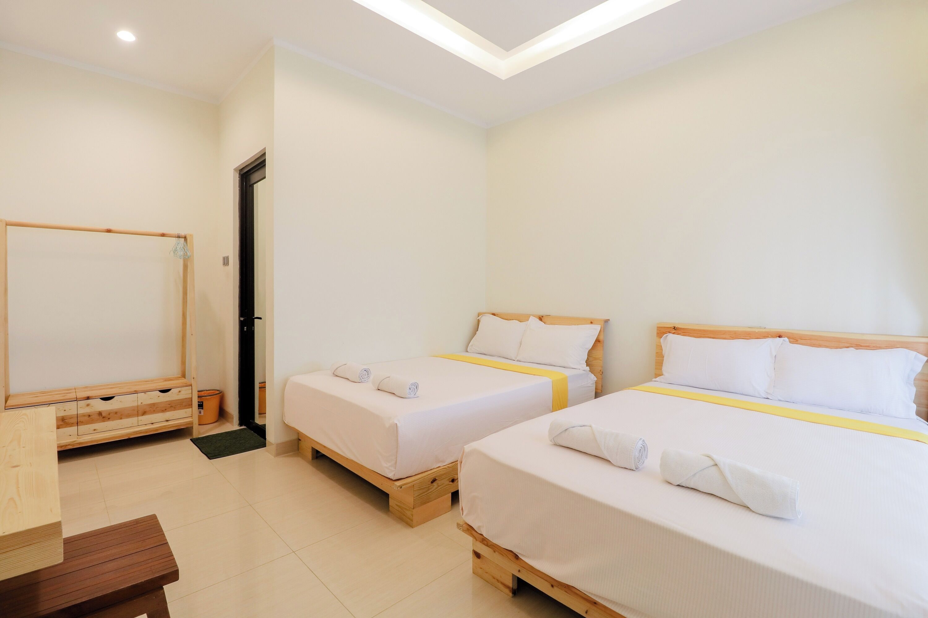 A hotel room with two beds, wooden furniture, and a small table.
