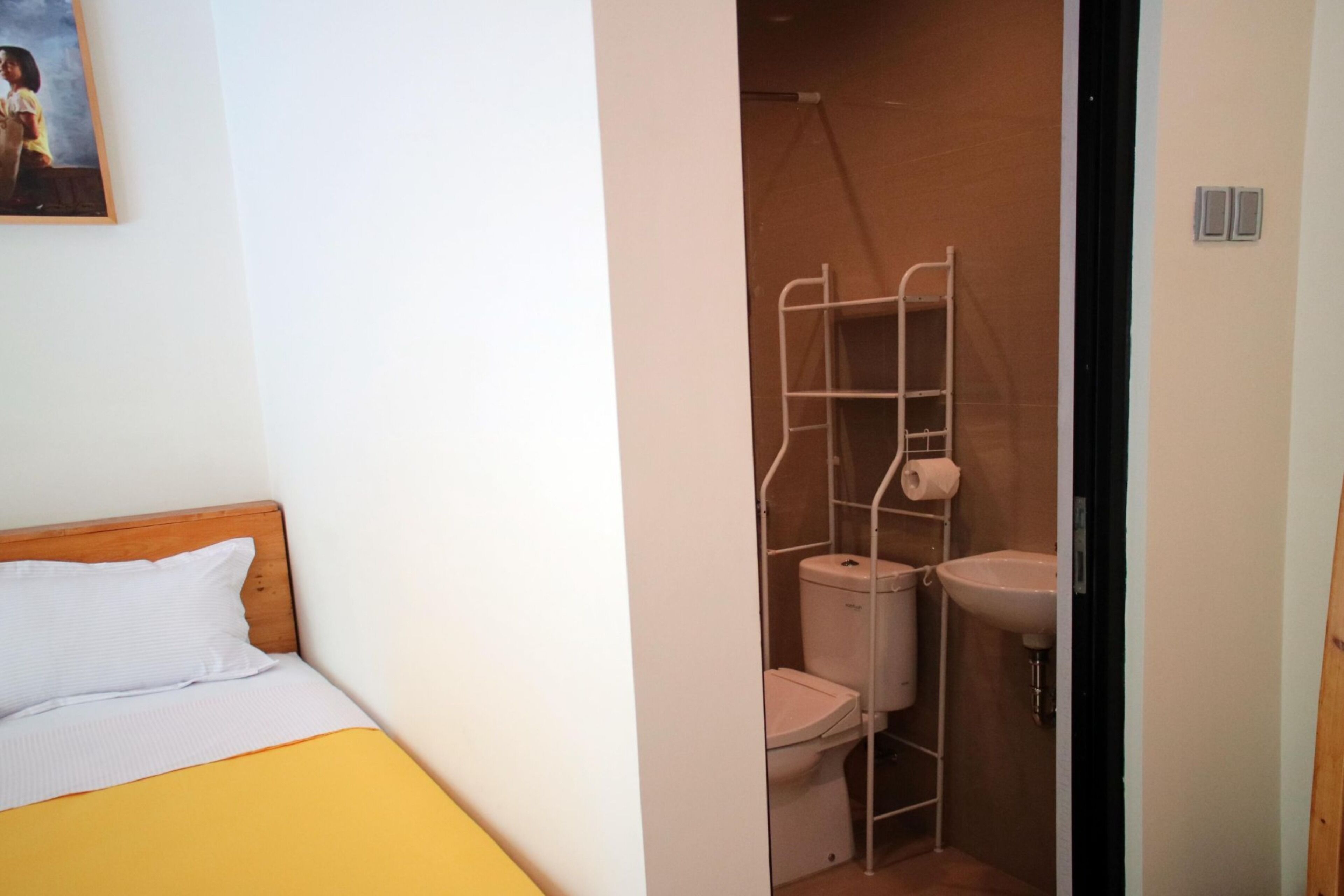 A small, compact room with a bed, a toilet, and a sink.