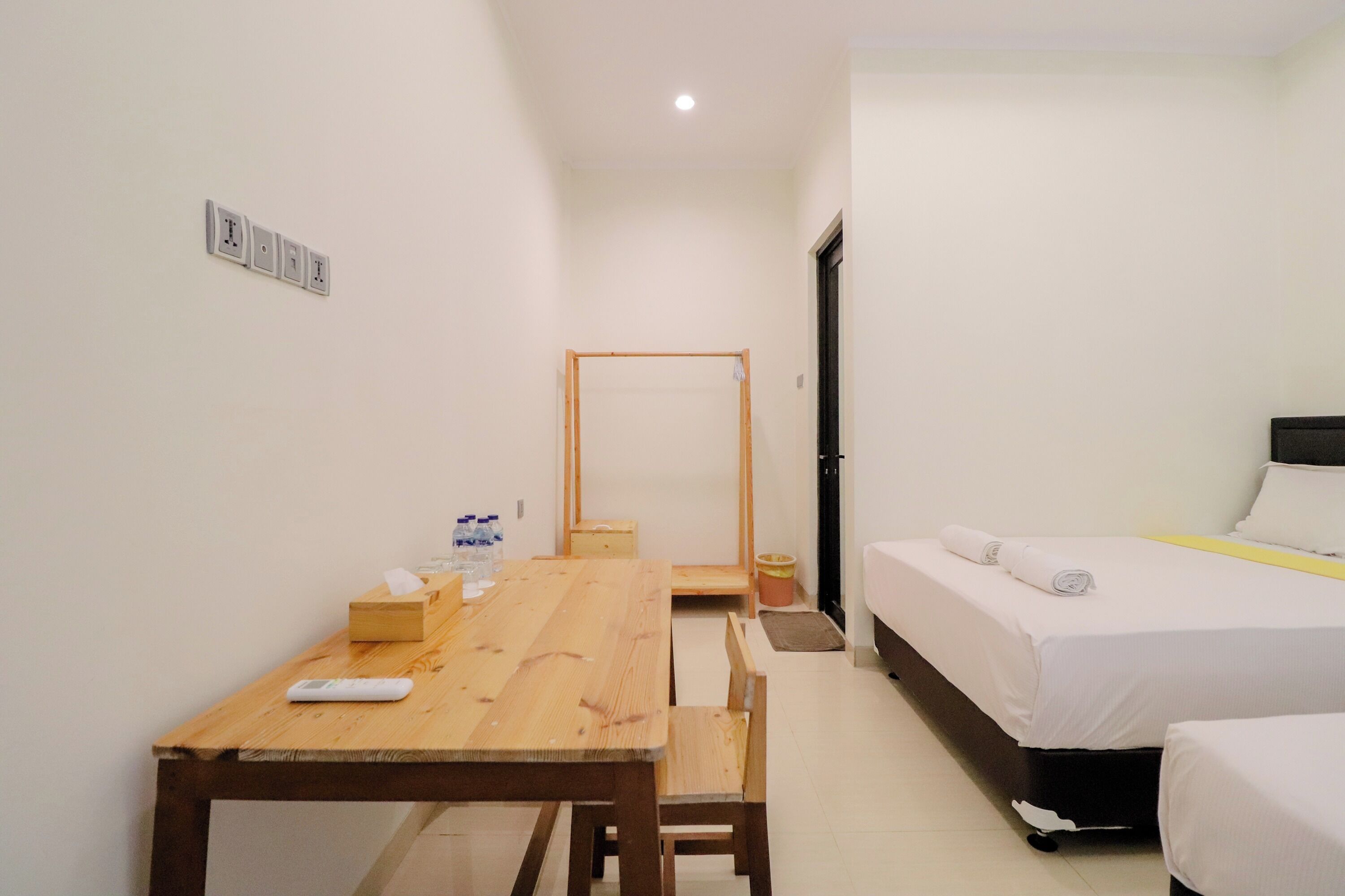 Een kleine, schone kamer met een houten tafel, een bed en een kledingkast.