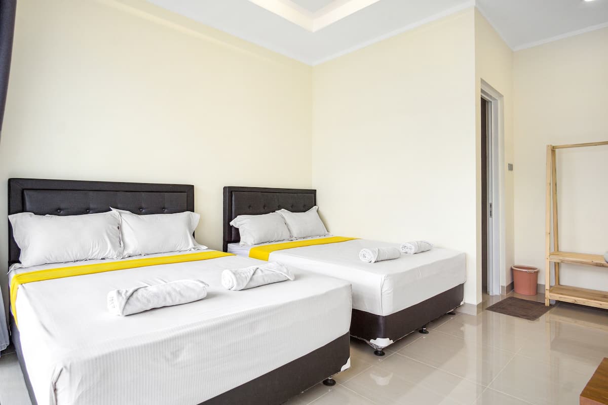 A hotel room with two beds, a wooden shelf, and a door.