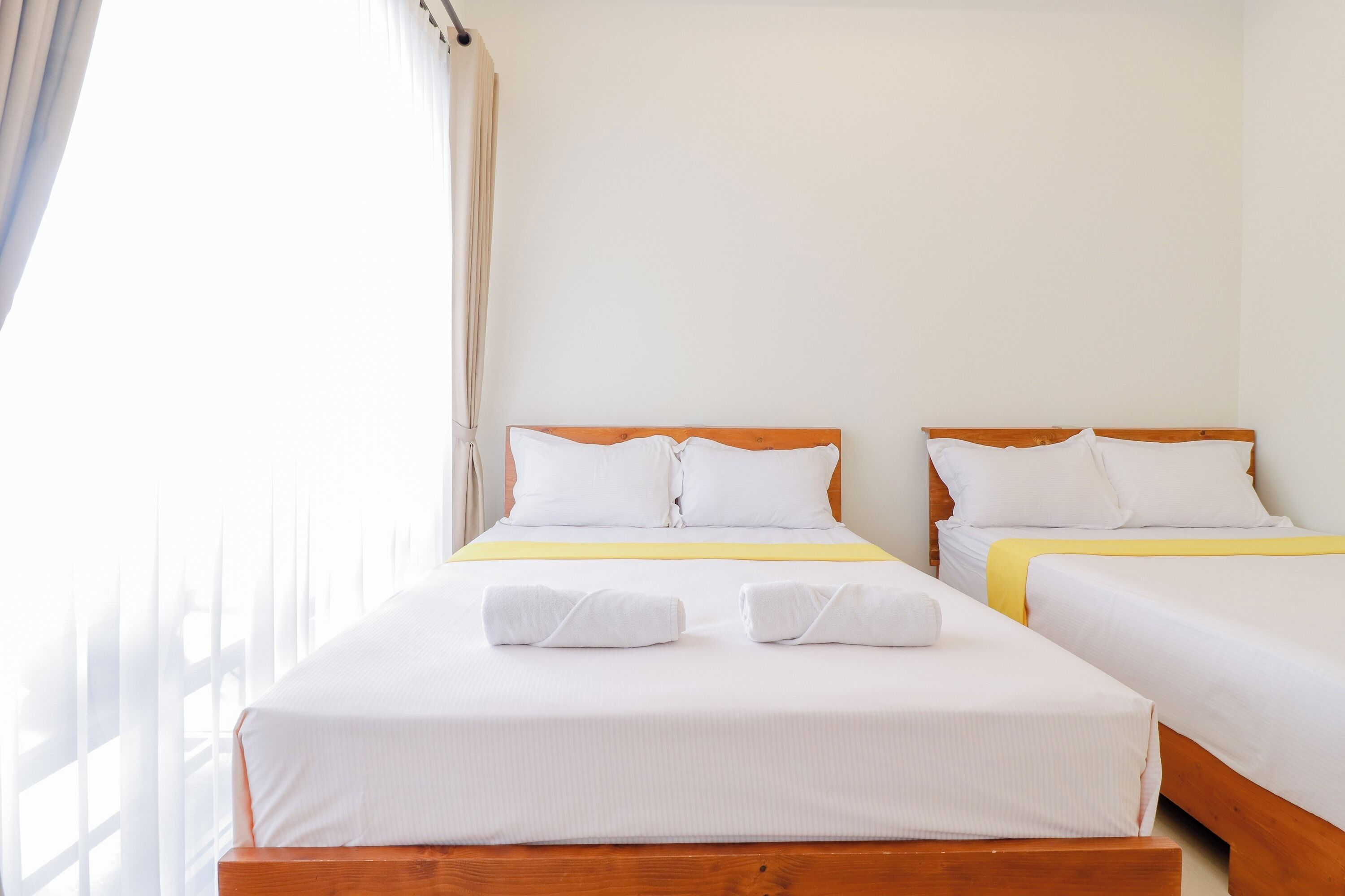 A hotel room with two beds, each with white bedding and wooden headboards.