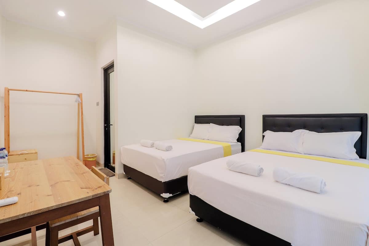 A hotel room with two beds, a wooden table, and a mirror.