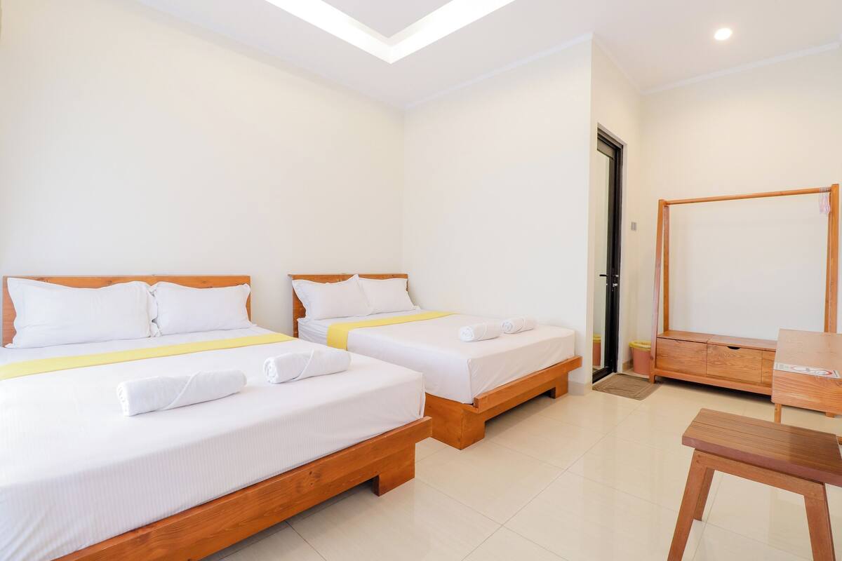 A hotel room with two single beds, a wooden desk, and a mirror.