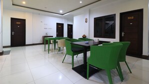 A hotel room with a tiled floor, green wicker chairs, a black table, and wooden doors numbered 2217 and 2218. - I Residence Bandung (Bandung)