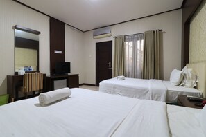 A hotel room with two beds, a desk with a TV, a mirror, and an air conditioning unit.
