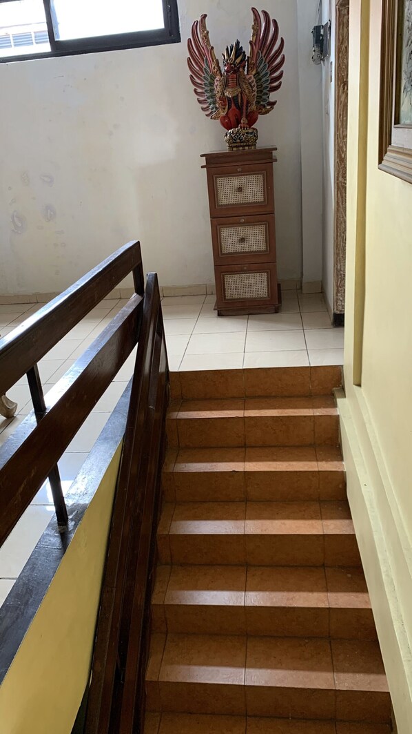 A staircase with a wooden handrail leading to a landing. A decorative statue is placed on the landing.