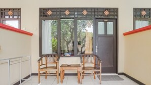 Una habitación con una puerta oscura, una mesita pequeña y dos sillas de madera.