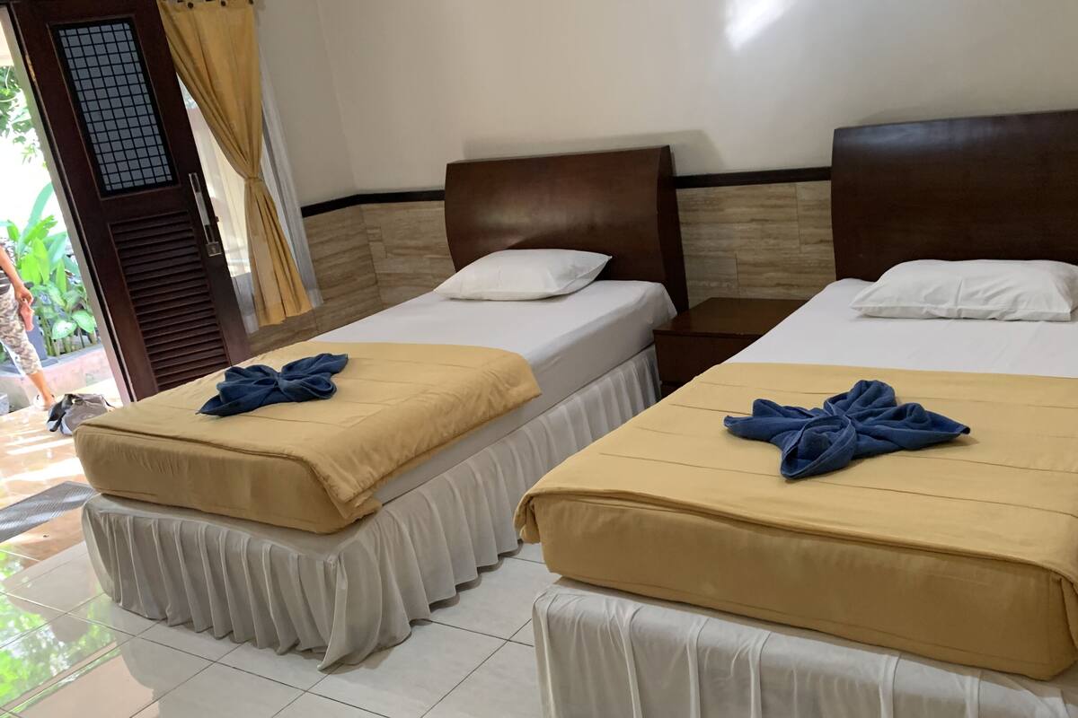 Two single beds with wooden headboards, beige and white bedding, and blue towels.