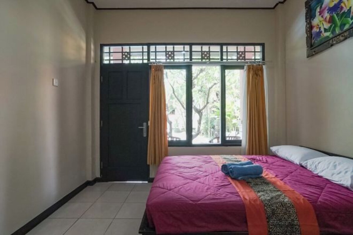 A bedroom with a bed, curtains, a window, and a door.