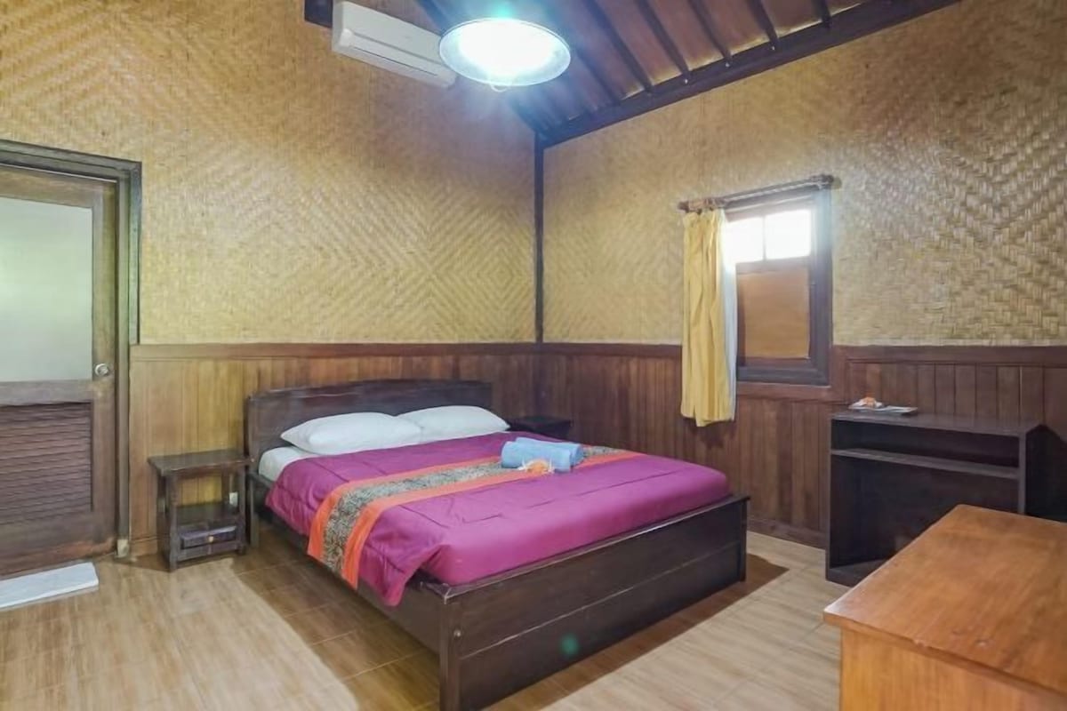 A wooden-framed room with a bed, a small bedside table, a nightstand, and a wooden cabinet.