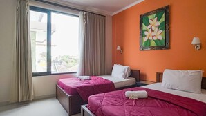 A hotel room with two beds, a large window with curtains, a painting on the wall, and a view of the outside. - Taxa Uma Guest House (Kuta)