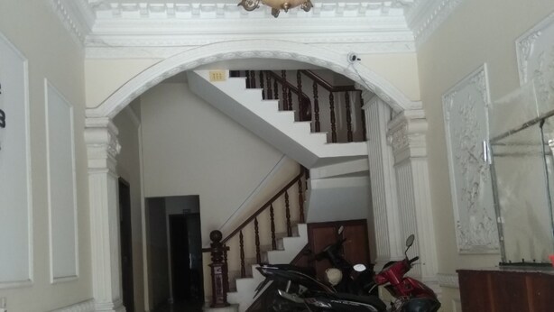 A grand hallway with a marble floor, a chandelier, a staircase, and two motorcycles parked near the stairs.