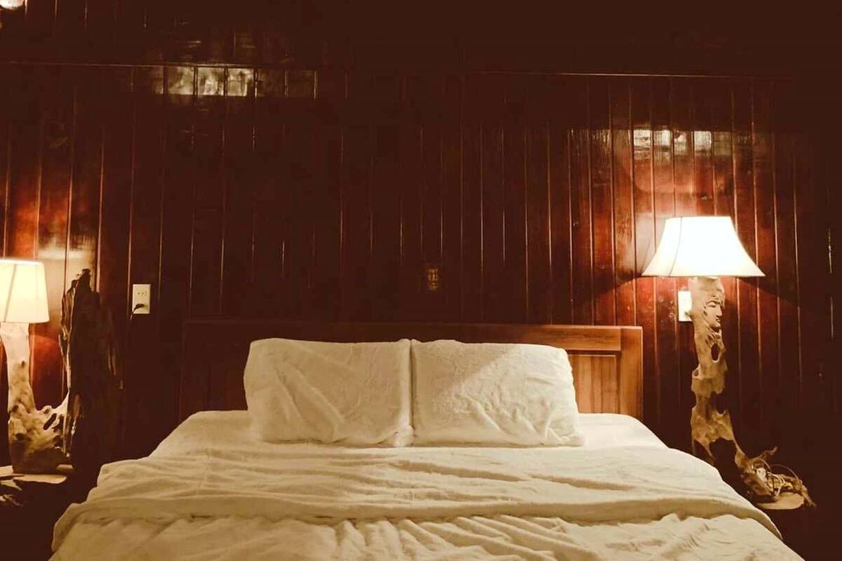 Ein Bett mit weißen Leinen in einem Zimmer mit Holzwandverkleidung.