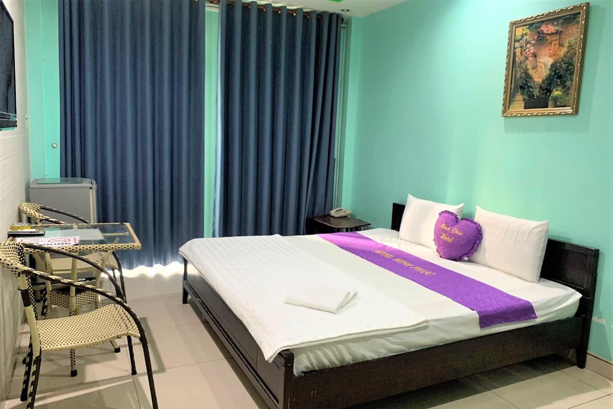 Une chambre d’hôtel avec un lit, un bureau et une chaise, un téléphone et un tableau au mur.