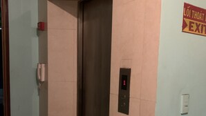 Un ascenseur doté d’un écran numérique, d’un extincteur et d’un panneau indiquant la sortie.