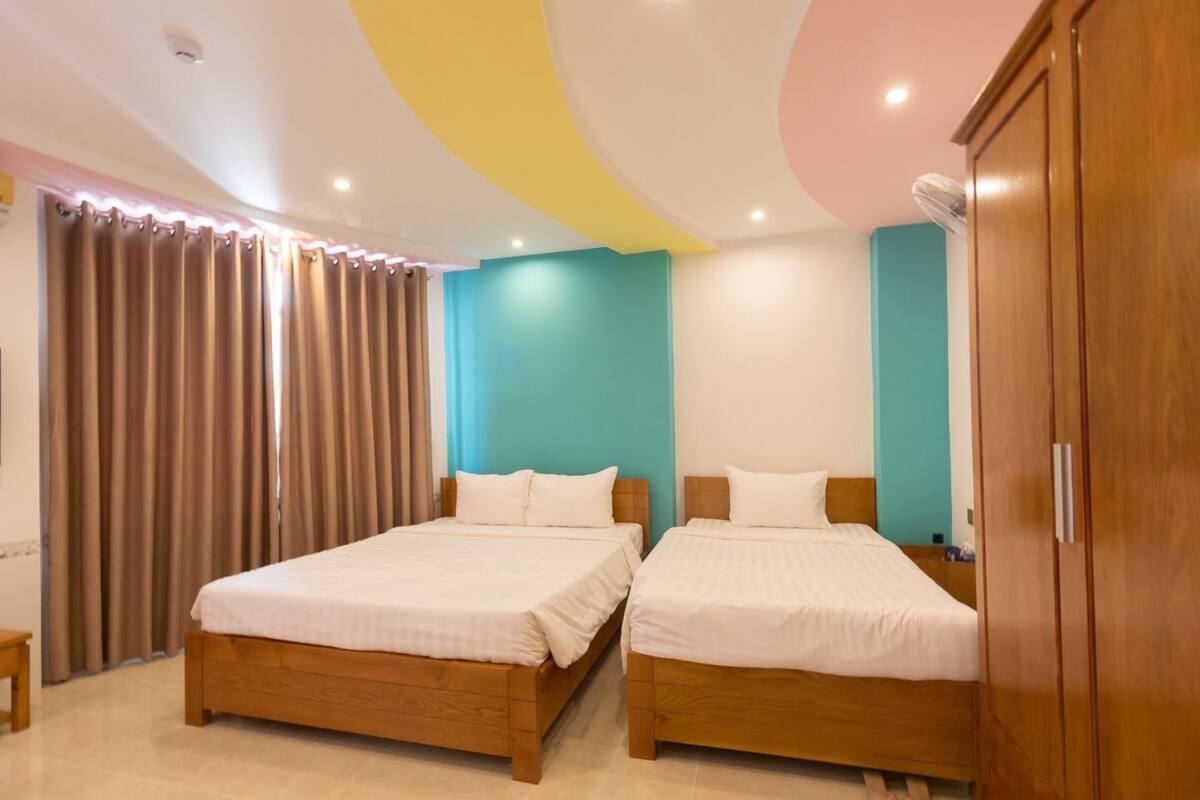 A room with two wooden beds, a wardrobe, and a ceiling with a circular design.