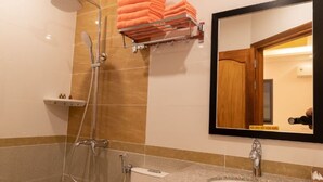 Een badkamer met douche, toilet, wastafel en een spiegel.