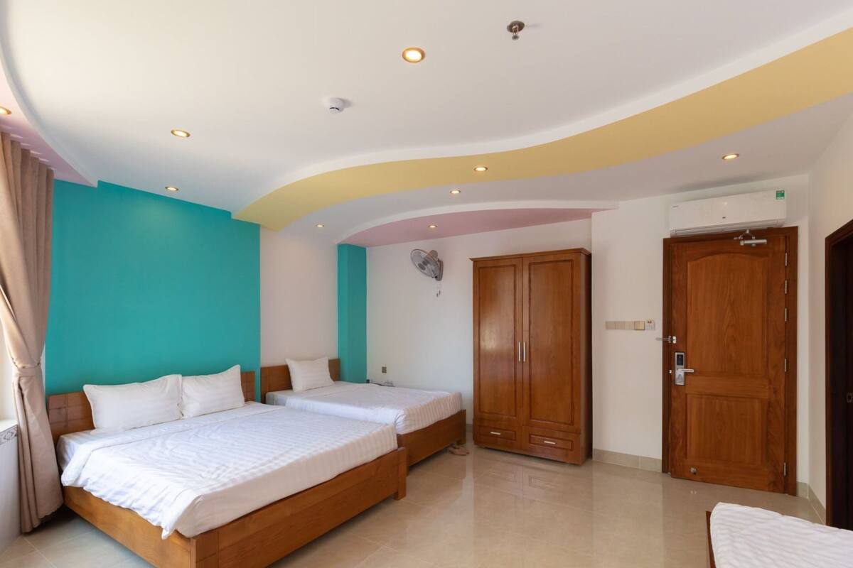 A hotel room with two beds, a wardrobe, and a ceiling with recessed lighting.