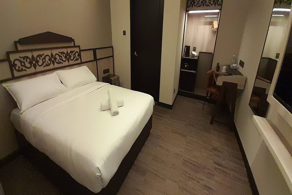 Une chambre d’hôtel avec un lit, un bureau, une chaise, un miroir et une porte.