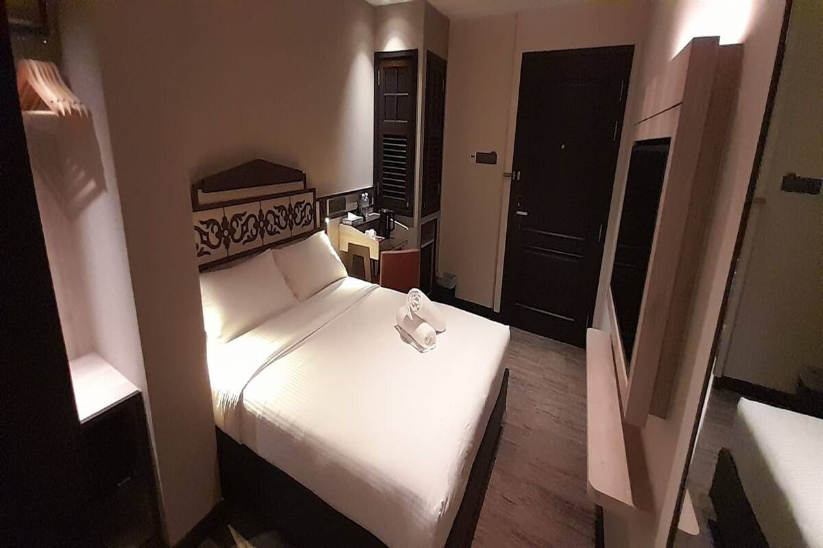 Une chambre d’hôtel avec un lit bien fait, une table de chevet, une armoire et une porte.