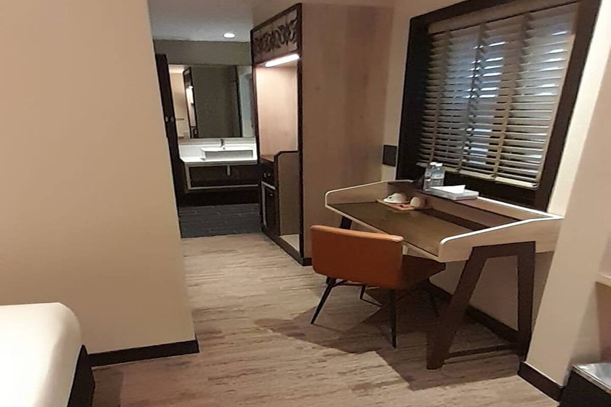 Une chambre à coucher avec un lit, un bureau et une fenêtre équipée de stores.