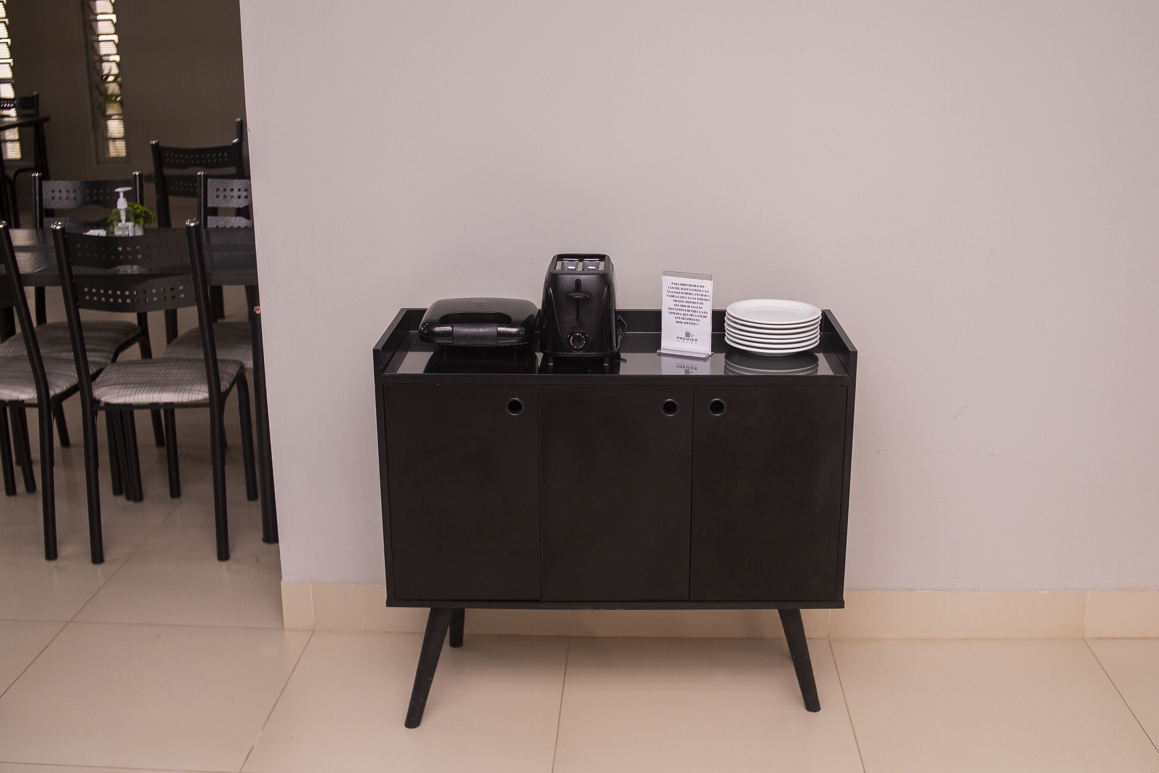 Una estación de buffet negra con una cafetera, platos y un cartel.